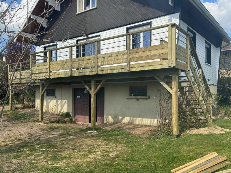 Construction d’une terrasse en pin autoclave sur pilotis en façade de maison à Thizy dans le Rhône.