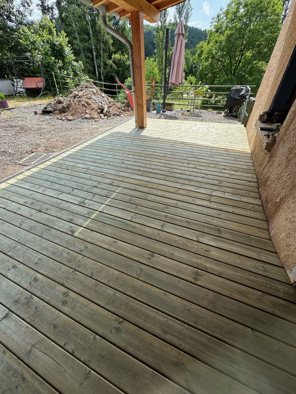 Réalisation d’une petite terrasse en pin autoclave sous abri et pose d’un caniveau à Chambost-Allières dans le Rhône.